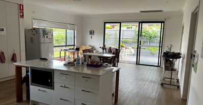 Accessible kitchen and dining area leading to covered outdoor entertainment area in Lifestyle Solutions three-bedroom Specialist Disability Accommodation (SDA) in Pallara, Qld
